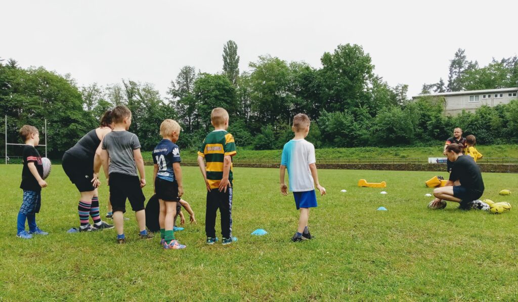 Gruppe von Kindern und Trainer*innen beim Rugbytraining im Waldstadion Trier.